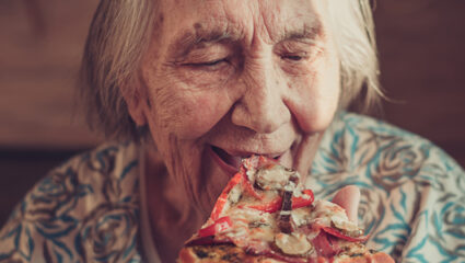 Oudere dame eet een pizzapunt